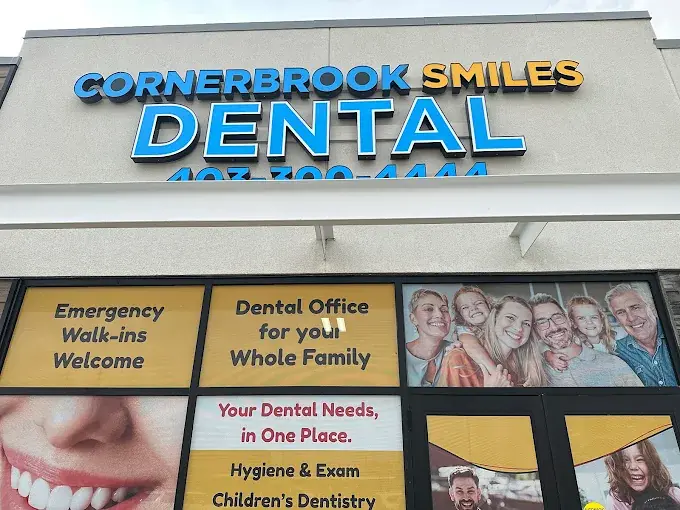 The illuminated Cornerbrook Smiles Dental sign above the entrance, over windows reading Emergency Walk-ins Welcome and Dental Office for your Whole Family